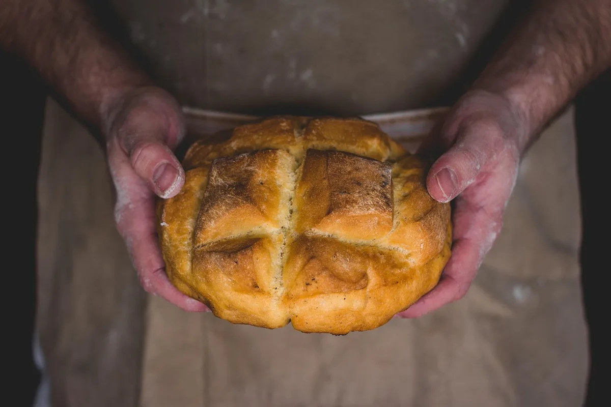 Mains anonymes de boulanger façonnant un pain au levain dans une boulangerie rustique
